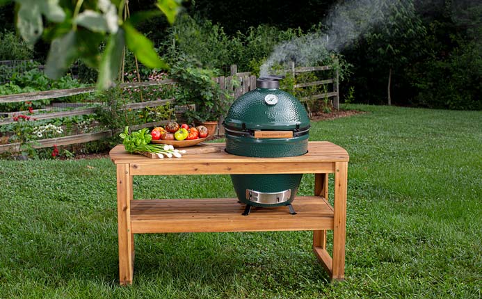 Big Green Egg in wooden stand with smoke