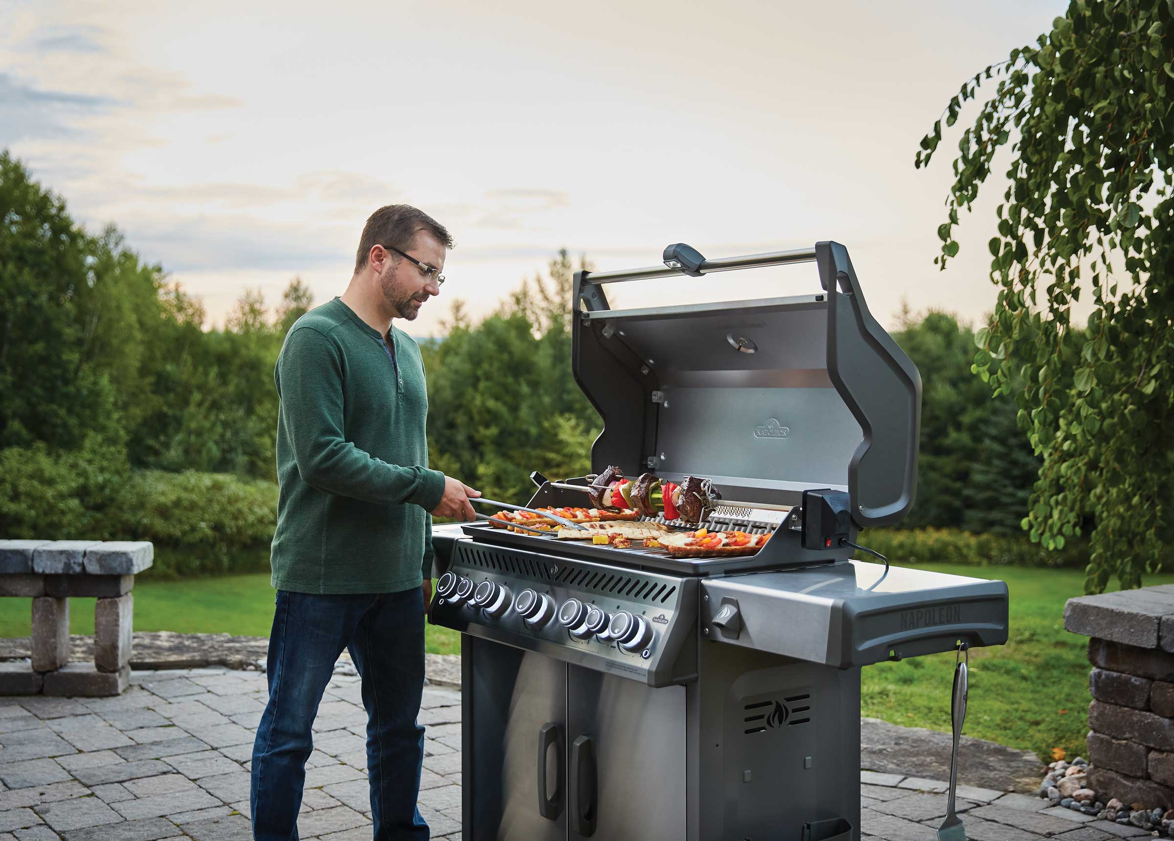 Man grilling on large Napoleon grill in evening